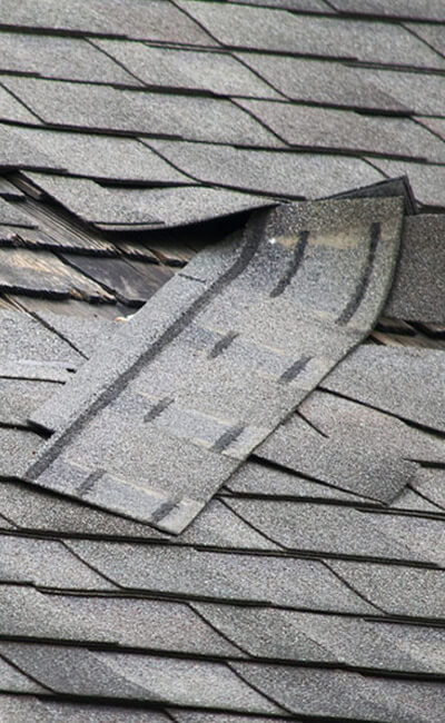 Broken and torn roof shingles from the wind