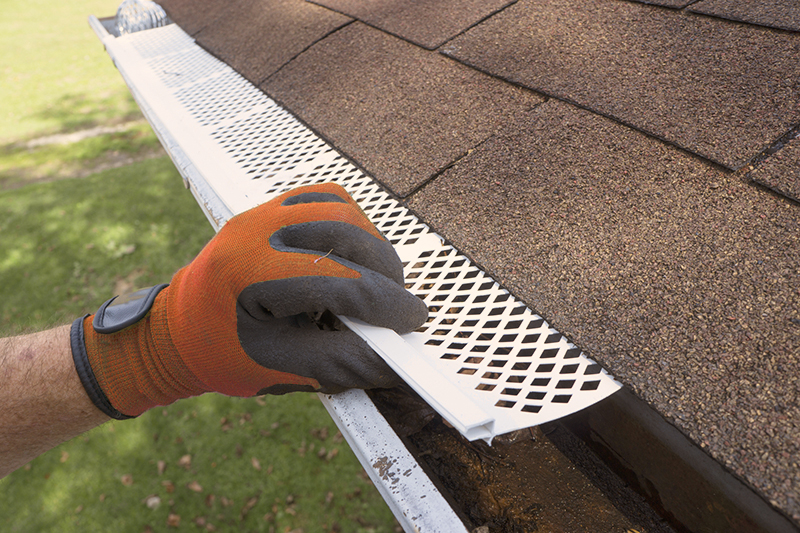 Person wearing gloves installing gutter guards