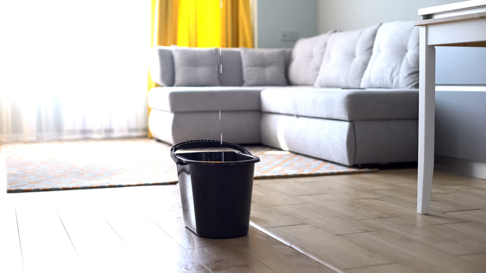 A bucket on the floor collects water from a spill up above.