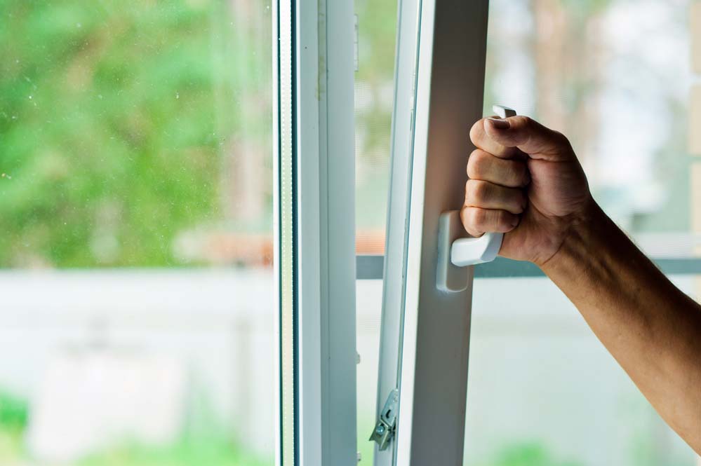 A hand opening a window by using a handle.