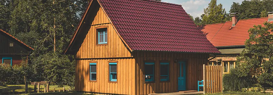 wood house with red metal barrel tile shingles