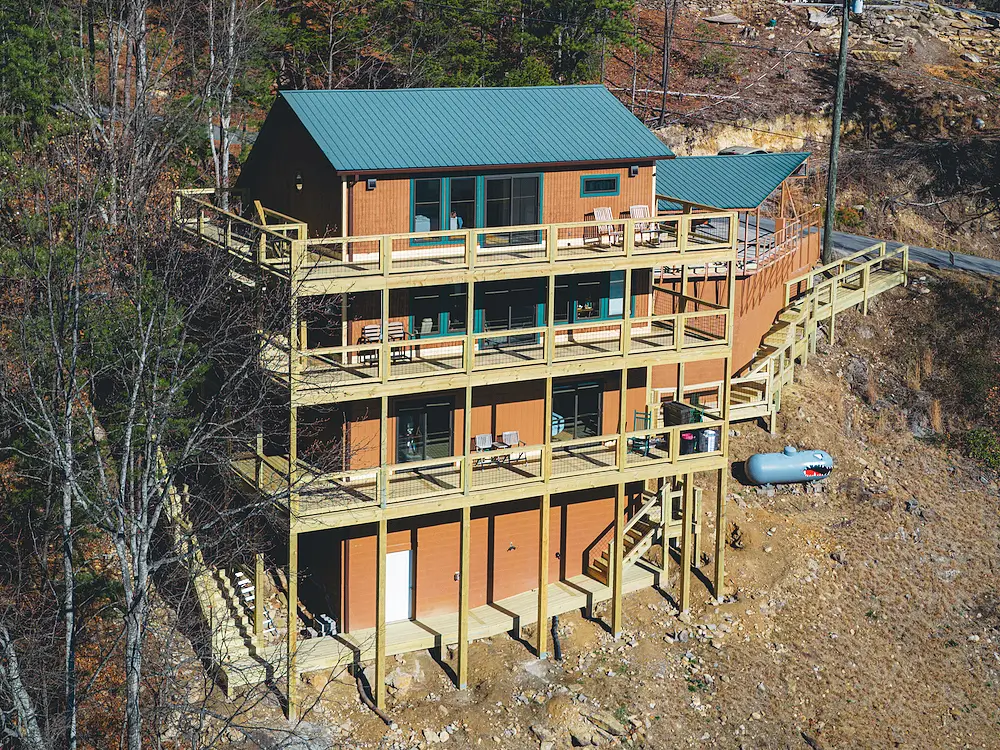 Completed multi-level deck in Sevierville as viewed from the exterior. Fresh pressure treated wood framing and decking. Hog-wire railing panels. Multiple levels visible stacked vertically.