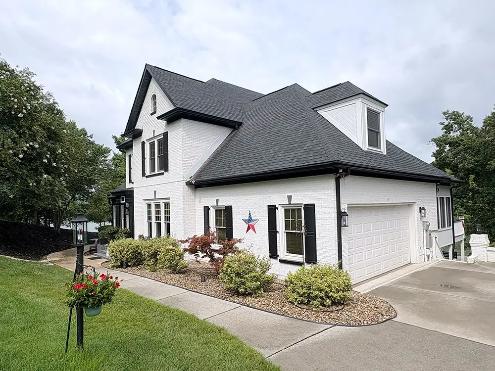 White brick Kingston home with a new dark dimensional shingle roof and black gutters and soffits